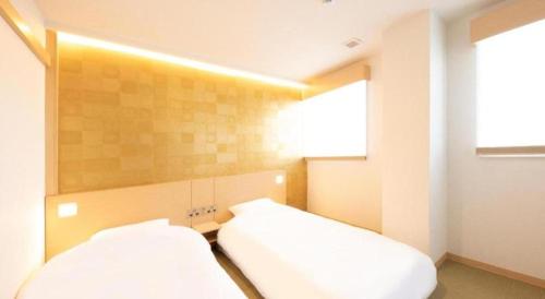 a bedroom with two white beds and a window at NAMBA EBISU HOTEL in Osaka