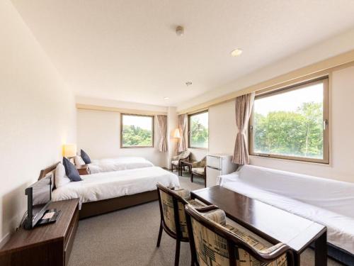 una camera d'albergo con due letti, un tavolo e delle sedie di Tabist Yabuki Station Hotel a Shirakawa