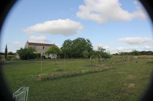 Les noyers في Saint-Savinien: حديقة بها أشجار في حقل به منزل