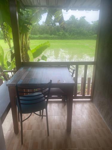 a table and a chair in a room with a window at สวรรค์บ้านนา คาเฟ่ ณ บ้านนา in Pakha