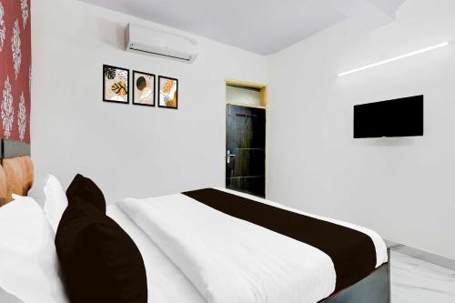 a white bedroom with a bed and a tv at Collection O Nehru Nagar in Ghaziabad
