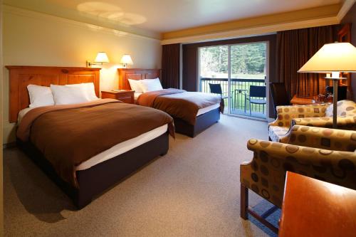 a hotel room with two beds and a balcony at Deer Lodge in Lake Louise