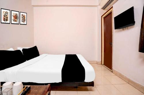 ein Schlafzimmer mit einem weißen Bett und einem Fernseher in der Unterkunft Collection O Vidhan Sabha Hussainganj in Lucknow