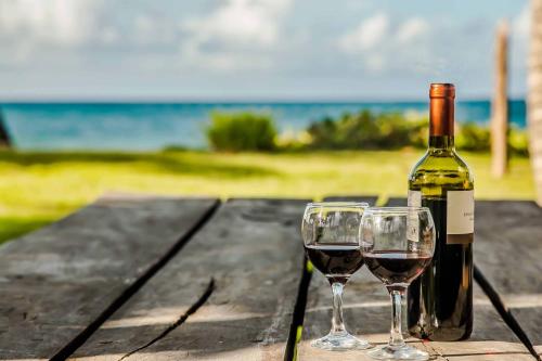 a bottle of wine and two glasses on a wooden table at Villa Ixora - Ocean Front in Las Galeras