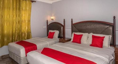two beds in a hotel room with red pillows at OYO 890 Hotel RK Cahaya in Labuan
