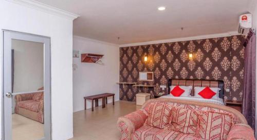 a bedroom with a bed with red pillows and a couch at Super OYO 1114 Neo Pegasus Hotel in Segamat