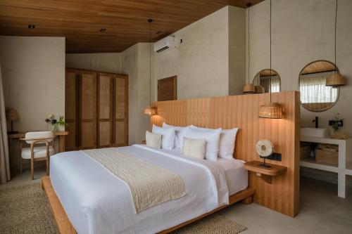 a bedroom with a large white bed and a desk at La Brava Bali I Private Luxury Villas in Bingin, Uluwatu in Uluwatu