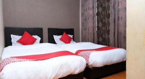 a bedroom with two beds with red pillows at OYO 44123 Hotel Al-Saif in Kuala Kerai