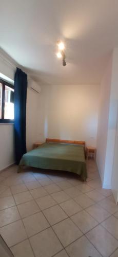 a bedroom with a green bed in a white room at ROMANTICA TOSCANA in Scarlino