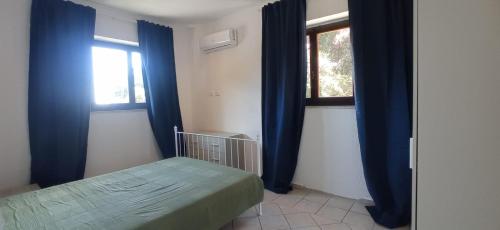 a bedroom with blue curtains and a bed and a window at ROMANTICA TOSCANA in Scarlino