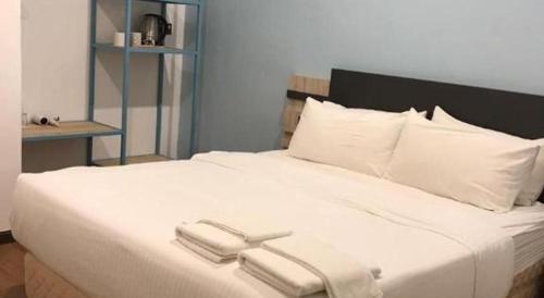 a large white bed with two white towels on it at TT Dorf Hotel (Taiping) in Taiping