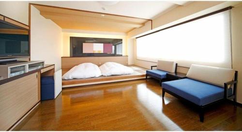 a living room with a bed and a television at Green Hotel Yes Nagahama Minatokan in Nagahama