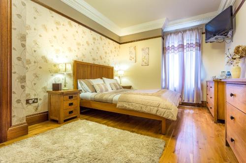 a bedroom with a bed and a dresser and a television at Thornbank House in Stranraer