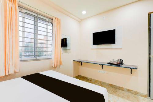 a room with a bed and a tv and a window at Townhouse MVP Circle Visakhapatnam in Visakhapatnam