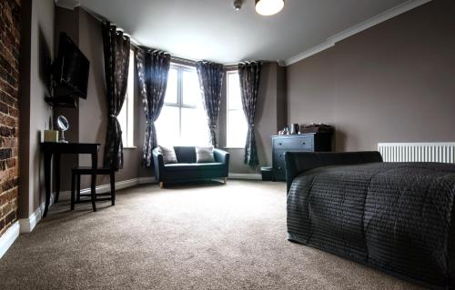 a bedroom with a bed and a chair and a window at shoreside inn in Shanklin