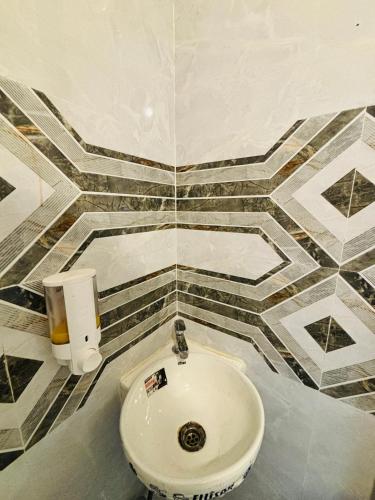 a bathroom with a sink and a tiled wall at Hotel Minar in Rohtak
