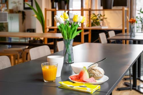 a table with a plate of fruit and a glass of orange juice at Forenom Hotels & Apartments Kista in Stockholm