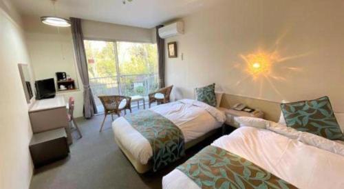 a hotel room with two beds and a desk and a window at Hotel Miyama in Chichibu