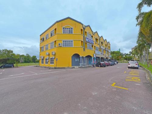 a yellow building with cars parked in a parking lot at OYO 90672 De Paradise Turtle Hotel in Kertih