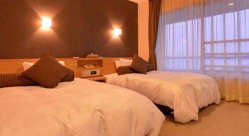 a hotel room with two beds and a window at Hamanako Lake Side Plaza in Hamamatsu