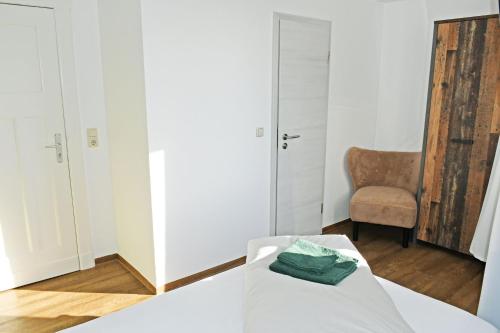 a bedroom with a white bed with a chair and a mirror at Baaber Hotel mit Frühstück in Baabe