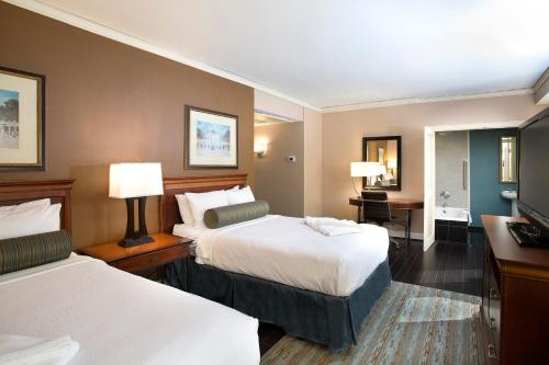 a hotel room with two beds and a desk at The Whitehall Houston in Houston