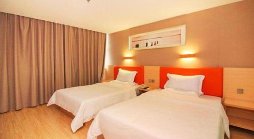 a hotel room with two beds and an orange wall at 7 Days Premium Zhuhai Gongbei Light Railway Branch in Zhuhai
