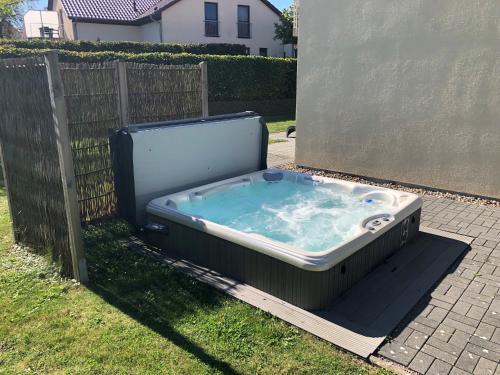 a hot tub sitting in the grass next to a fence at Lontargos OG Wohnung in Göhren-Lebbin