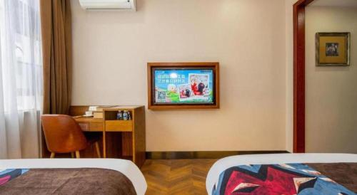 a hotel room with a desk and a bed and a television at James Joyce Coffetel·Lijiang Old Town Centeral in Lijiang