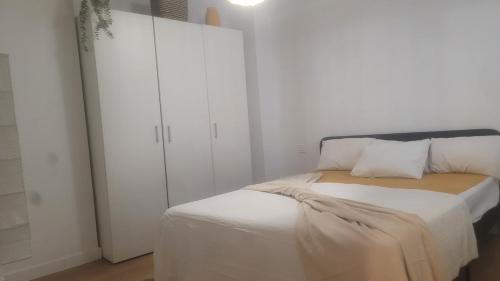a white bedroom with a bed with a white closet at Dúplex soleado cerca del mar in Santoña