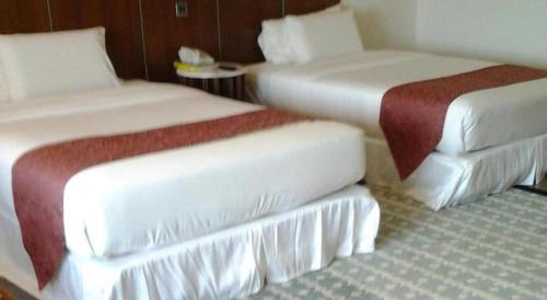 a hotel room with two beds and a table at Century Helang Hotel in Pantai Cenang