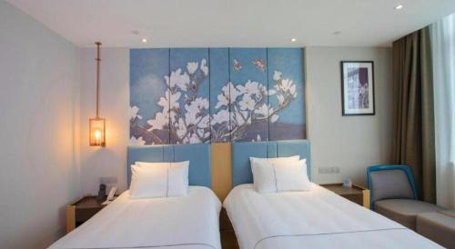 two beds in a hotel room with a painting on the wall at Magnotel Hotel Dongxing Guomen Port in Fangcheng