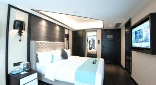 a bedroom with a large white bed and a flat screen tv at Xana Hotelle Zhuhai Gongbei Port in Zhuhai
