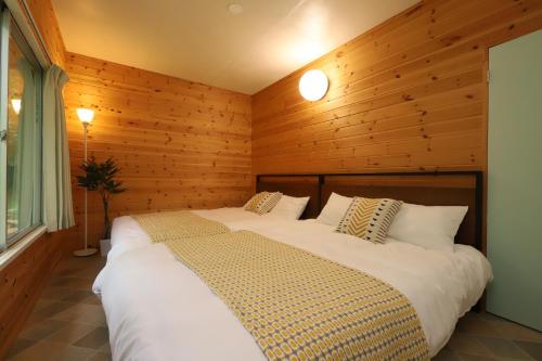 a bedroom with a large bed in a wooden wall at Forest Twin Cabin in Tsumagoi