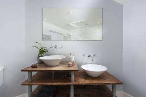 a bathroom with two sinks on a wooden table at Berlewen, Mousehole in Mousehole