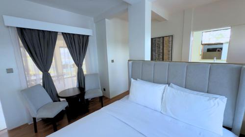 a bedroom with a white bed and a chair and window at Whiterock Beach Hotel and Waterpark in Subic