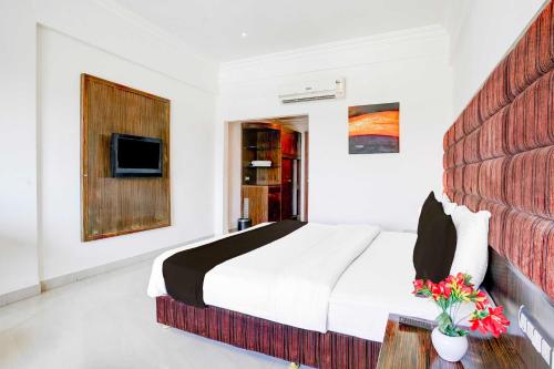 una camera da letto bianca con un letto e una TV di Super Townhouse Bharuch Railway Station a Bharuch