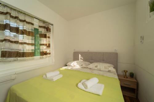 a bedroom with a green bed with towels on it at Piazza dei Signori in Zadar