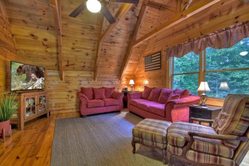 a living room with pink furniture in a log cabin at Buffalo Ridge Fish in the pond soak in the hot tub in Mineral Bluff