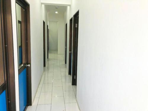 a hallway with many doors and a white tile floor at SPOT ON 90077 Cherry's Lodge in Lahad Datu