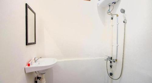 a white bathroom with a sink and a shower at Super OYO 1788 House 24 in Yogyakarta