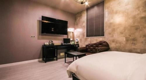 a bedroom with a bed and a desk and a television at Hotel Seowa in Gimhae