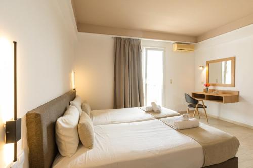 a hotel room with two beds and a desk at Pelagia Bay Hotel in Agia Pelagia
