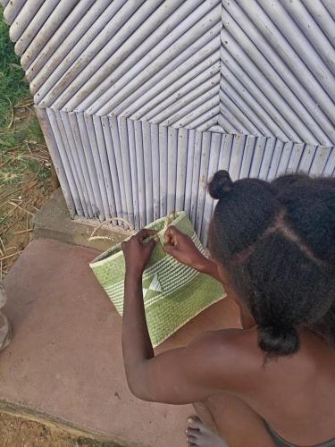 a woman sitting on the ground holding a book at Vivez comme nous chez nous in Sambava