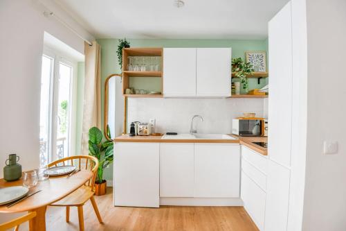 une cuisine avec des armoires blanches et une table en bois dans l'établissement Le Glandèves - Appart standing proche Vieux-Port, à Marseille