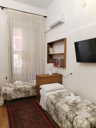 a bedroom with two beds and a flat screen tv at PALAZZO FULGHER in Cagliari