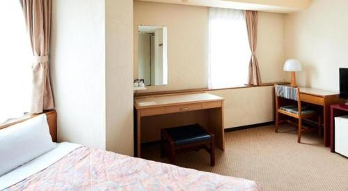 a hotel room with a bed and a desk and a mirror at Marroad Inn Tokyo in Chofu