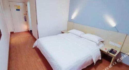 a bedroom with a white bed with two pillows at 7 Days Inn Guilin Beiji Plaza Yushan Garden in Guilin