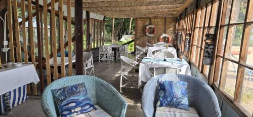 a restaurant with tables and chairs in a building at Norman Carr Cottage in Monkey Bay