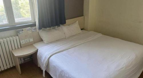 a white bed in a small room with a window at 7 Days Inn Hami Baofeng Market in Qumul